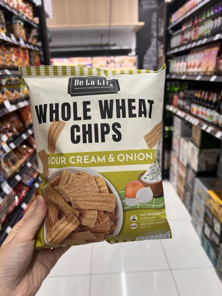 Delalita whole wheat chips sour cream onion flavor bag closeup,
Thai healthy snack, green and white packaging, natural light product photography