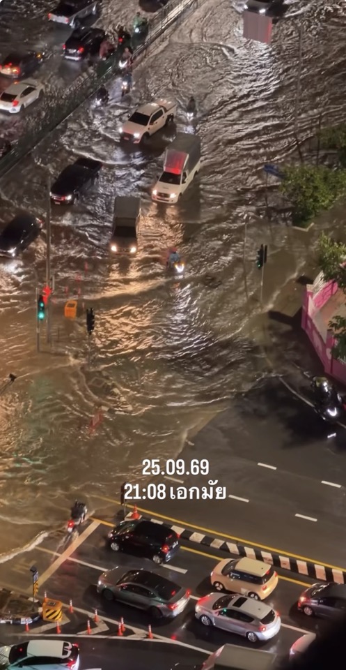 A night view of a flooded city street on September 25, 2025. The street is submerged in water, and driving cars are visible. Thai text is superimposed over the image.